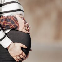 A pregnant woman in a striped shirt and black pants