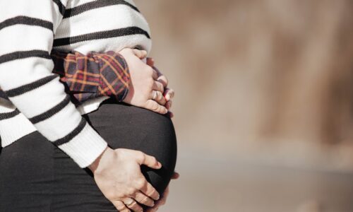 A pregnant woman in a striped shirt and black pants